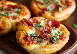 Mini deep dish crescent roll pizzas baked in muffin tins, filled with marinara sauce, melted mozzarella, and pepperoni, served hot and golden brown.