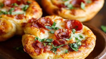 Mini deep dish crescent roll pizzas baked in muffin tins, filled with marinara sauce, melted mozzarella, and pepperoni, served hot and golden brown.
