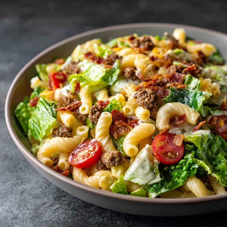 Big Mac Pasta Salad with ground beef, cheddar cheese, lettuce, pickles, and creamy special sauce in a colorful bowl.