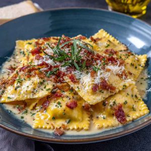 Olive Garden-inspired ravioli carbonara crunch served in a skillet with crispy breadcrumbs, creamy carbonara sauce, cheese-filled ravioli, and garnished with parsley.