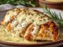 Golden pan-seared chicken breasts topped with creamy melted cheese sauce, served on a plate with fresh herbs and roasted vegetables.