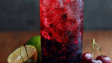 Midnight Malibu dirty soda served in a tall glass with ice, layered with cola, coconut cream, and lime, garnished with a lime wedge for a refreshing tropical twist.