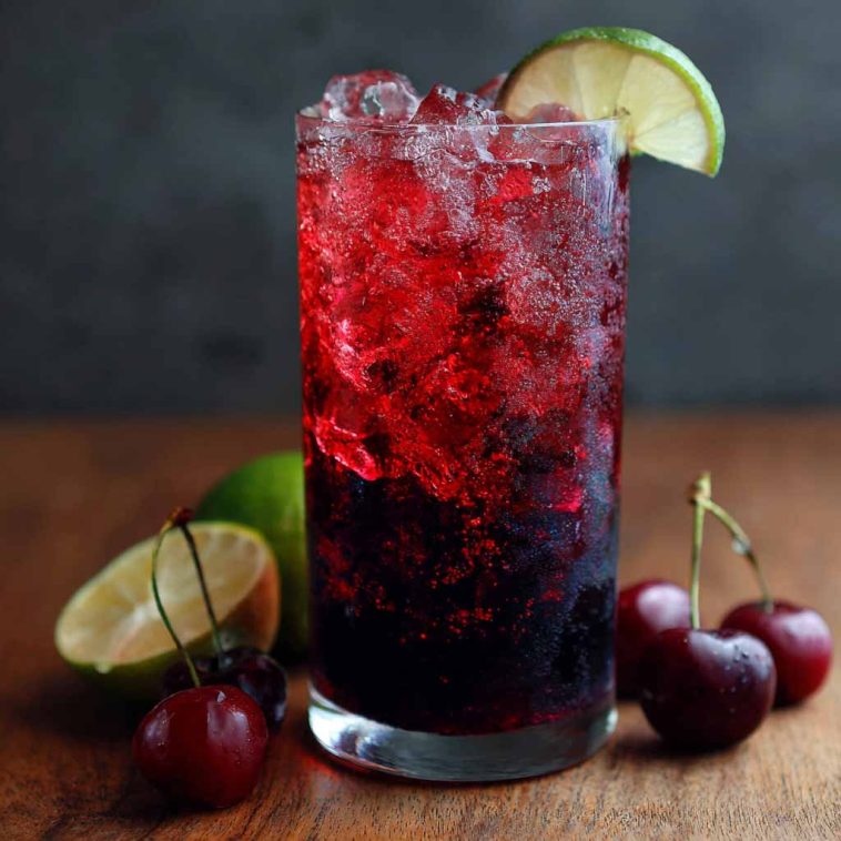 Midnight Malibu dirty soda served in a tall glass with ice, layered with cola, coconut cream, and lime, garnished with a lime wedge for a refreshing tropical twist.