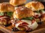 Hot Italian sub sliders baked golden brown with layers of salami, pepperoni, ham, melted cheese, and Italian seasoning, served on slider buns with a buttery glaze.