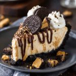 Unbelievable peanut butter pie with Oreo crust and creamy filling, topped with whipped cream and mini peanut butter cups, served chilled on a dessert plate.