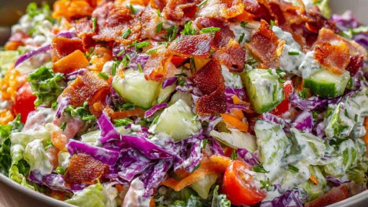 Bacon ranch chopped salad with lettuce, tomatoes, cheese, and crispy bacon pieces in a bowl.