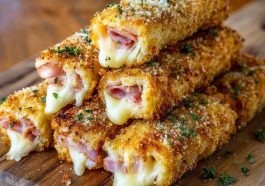 Golden baked ham and cheese sticks with melted cheese and savory ham wrapped in flaky pastry, served warm with dipping sauce.