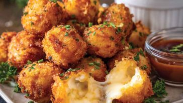 Golden brown fried cheese bites with a crispy coating and gooey melted cheese inside, served on a platter with dipping sauces.