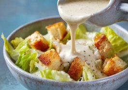 Homemade Caesar dressing made with cottage cheese, blended until creamy, served in a glass jar with fresh romaine lettuce and Parmesan cheese on the side.