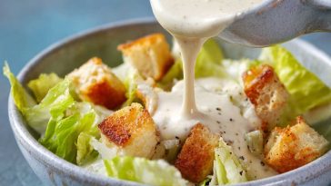Homemade Caesar dressing made with cottage cheese, blended until creamy, served in a glass jar with fresh romaine lettuce and Parmesan cheese on the side.
