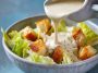 Homemade Caesar dressing made with cottage cheese, blended until creamy, served in a glass jar with fresh romaine lettuce and Parmesan cheese on the side.