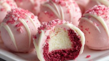No-bake pink velvet cheesecake bites topped with whipped cream and sprinkles, served on a tray as bite-sized desserts with a creamy pink filling and cookie crust.