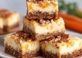 Cream cheese bars with carrot cake flavor, topped with creamy frosting and sprinkled with cinnamon, served on a tray with fresh carrot shavings.