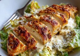 Creamy Parmesan baked Caesar chicken served in a casserole dish, garnished with fresh parsley.