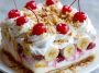 Slice of no bake banana split cake topped with whipped cream, nuts, and a cherry.