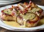 Maple bacon pork chops topped with creamy Dijon mustard sauce, served in a skillet with crispy bacon pieces and fresh herbs for a savory comfort food dish.