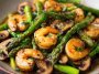 Shrimp and Asparagus Stir-Fry with Mushrooms cooked in a savory sauce, served in a skillet with vibrant green asparagus and tender shrimp.