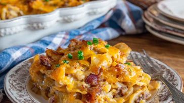 Amish harvest casserole baked golden brown in a rustic dish, filled with layers of ground beef, vegetables, rice, and a savory sauce, topped with melted cheese.