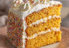 Cornbread cake topped with fluffy whipped honey buttercream frosting, baked golden brown and garnished with a drizzle of honey and fresh herbs for a rustic presentation.