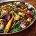 Spring salad with roasted veggies served in a bowl, featuring colorful roasted carrots, zucchini, bell peppers, cherry tomatoes, and fresh greens topped with a light vinaigrette.