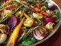 Spring salad with roasted veggies served in a bowl, featuring colorful roasted carrots, zucchini, bell peppers, cherry tomatoes, and fresh greens topped with a light vinaigrette.