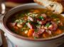 Hearty ham and bean soup with tender beans, smoky ham chunks, carrots, celery, and herbs simmered in a savory broth, served in a rustic bowl.