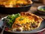 One-pan cheeseburger pie dinner baked golden brown in a skillet, layered with ground beef, cheese, and biscuit crust, garnished with fresh parsley.