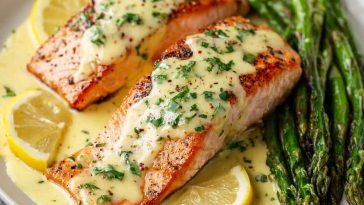 Baked salmon fillet topped with creamy lemon butter sauce, garnished with fresh parsley and lemon slices, served with roasted vegetables.