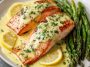 Baked salmon fillet topped with creamy lemon butter sauce, garnished with fresh parsley and lemon slices, served with roasted vegetables.