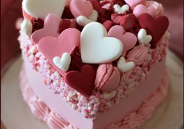 Homemade Valentines Day cakes decorated with pink and red frosting, heart-shaped designs, and festive sprinkles arranged beautifully on a dessert table.