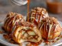 Simple caramel apple pie bombs baked golden brown, filled with gooey caramel, spiced apples, and flaky pastry, served warm with a drizzle of caramel sauce.