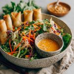 Spring roll salad with rice noodles, fresh vegetables, and spicy ginger dressing served in a bowl.