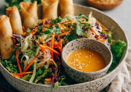 Spring roll salad with rice noodles, fresh vegetables, and spicy ginger dressing served in a bowl.