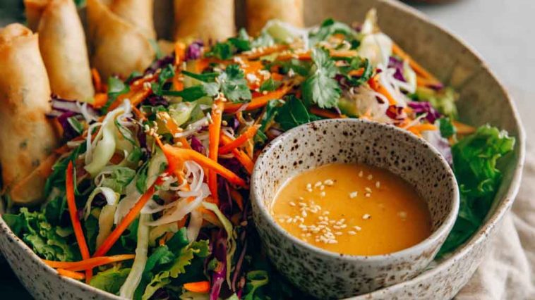 Spring roll salad with rice noodles, fresh vegetables, and spicy ginger dressing served in a bowl.