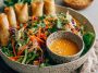 Spring roll salad with rice noodles, fresh vegetables, and spicy ginger dressing served in a bowl.