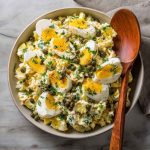 Lemon caper egg salad served in a bowl with chopped hard-boiled eggs, creamy dressing, tangy capers, and fresh herbs, garnished with lemon zest and parsley.