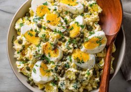 Lemon caper egg salad served in a bowl with chopped hard-boiled eggs, creamy dressing, tangy capers, and fresh herbs, garnished with lemon zest and parsley.