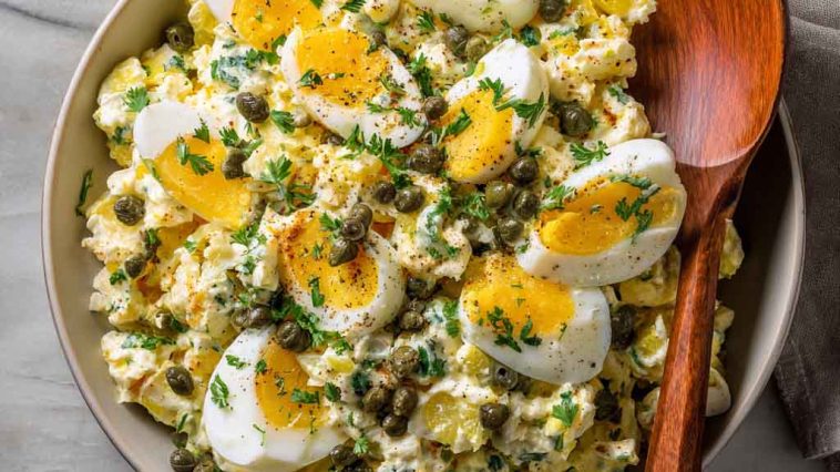 Lemon caper egg salad served in a bowl with chopped hard-boiled eggs, creamy dressing, tangy capers, and fresh herbs, garnished with lemon zest and parsley.