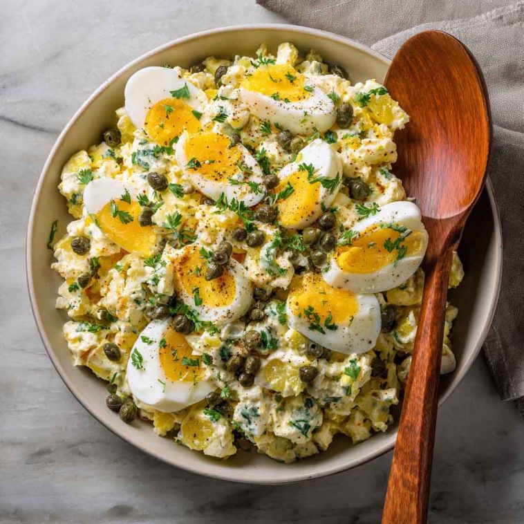 Lemon caper egg salad served in a bowl with chopped hard-boiled eggs, creamy dressing, tangy capers, and fresh herbs, garnished with lemon zest and parsley.