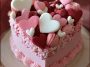 Homemade Valentines Day cakes decorated with pink and red frosting, heart-shaped designs, and festive sprinkles arranged beautifully on a dessert table.