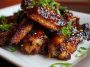 Sticky pineapple-teriyaki chicken wings glazed with sweet and savory sauce, garnished with sesame seeds and green onions, served on a rustic platter.