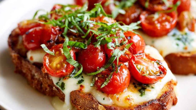 Tomato basil mozzarella toast made with crusty bread topped with fresh mozzarella, ripe tomato slices, basil leaves, and a drizzle of olive oil, served golden and crisp.