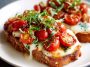 Tomato basil mozzarella toast made with crusty bread topped with fresh mozzarella, ripe tomato slices, basil leaves, and a drizzle of olive oil, served golden and crisp.