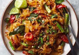 Street style Thai drunken noodles stir-fried in a wok, with wide rice noodles, colorful bell peppers, Thai basil, and chili sauce, served hot and spicy.