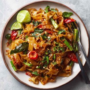 Street style Thai drunken noodles stir-fried in a wok, with wide rice noodles, colorful bell peppers, Thai basil, and chili sauce, served hot and spicy.