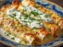 Chicken Enchiladas with Sour Cream White Sauce baked in a casserole dish, topped with melted cheese and fresh herbs.