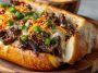 Spicy kimchi bulgogi cheesesteak served on a toasted hoagie roll, filled with marinated beef bulgogi, melted cheese, sautéed onions, and tangy kimchi, garnished with sesame seeds.