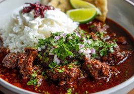 Beef chile colorado served in a rustic bowl with tender beef chunks simmered in a rich red chile sauce, garnished with cilantro and served alongside warm tortillas.