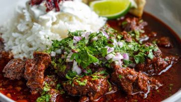 Beef chile colorado served in a rustic bowl with tender beef chunks simmered in a rich red chile sauce, garnished with cilantro and served alongside warm tortillas.