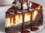 The best brownie cheesecake sliced on a plate, with fudgy brownie layers, creamy cheesecake filling, and a drizzle of chocolate ganache topped with whipped cream.